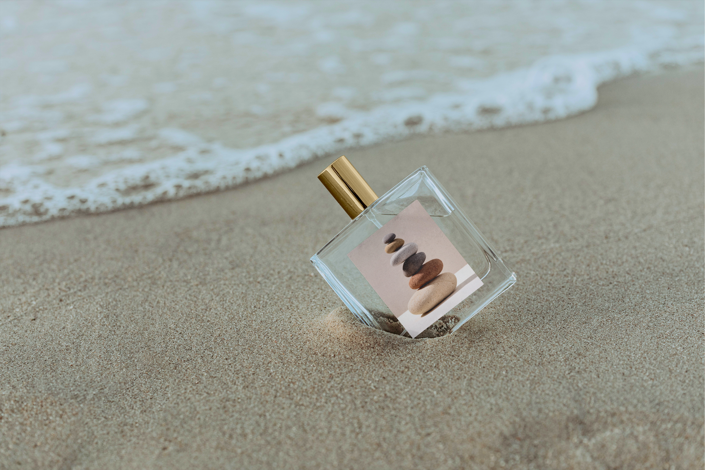 Perfume bottle with a beach-themed label on a sandy beach with waves.