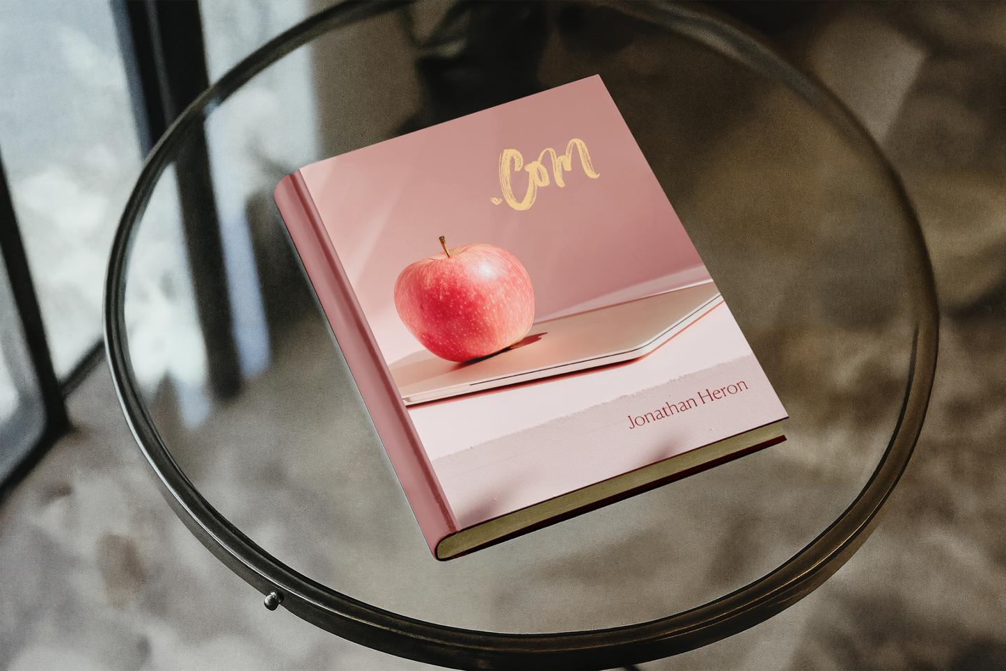 Pink book with an apple on a glass table