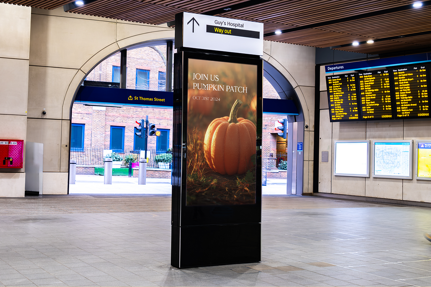 Digital display board with a pumpkin advertisement in a train station.