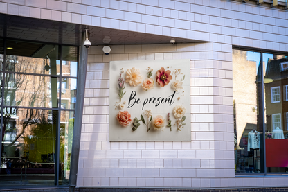 Decorative wall art with floral designs and 'Be present' text on a tiled building exterior.