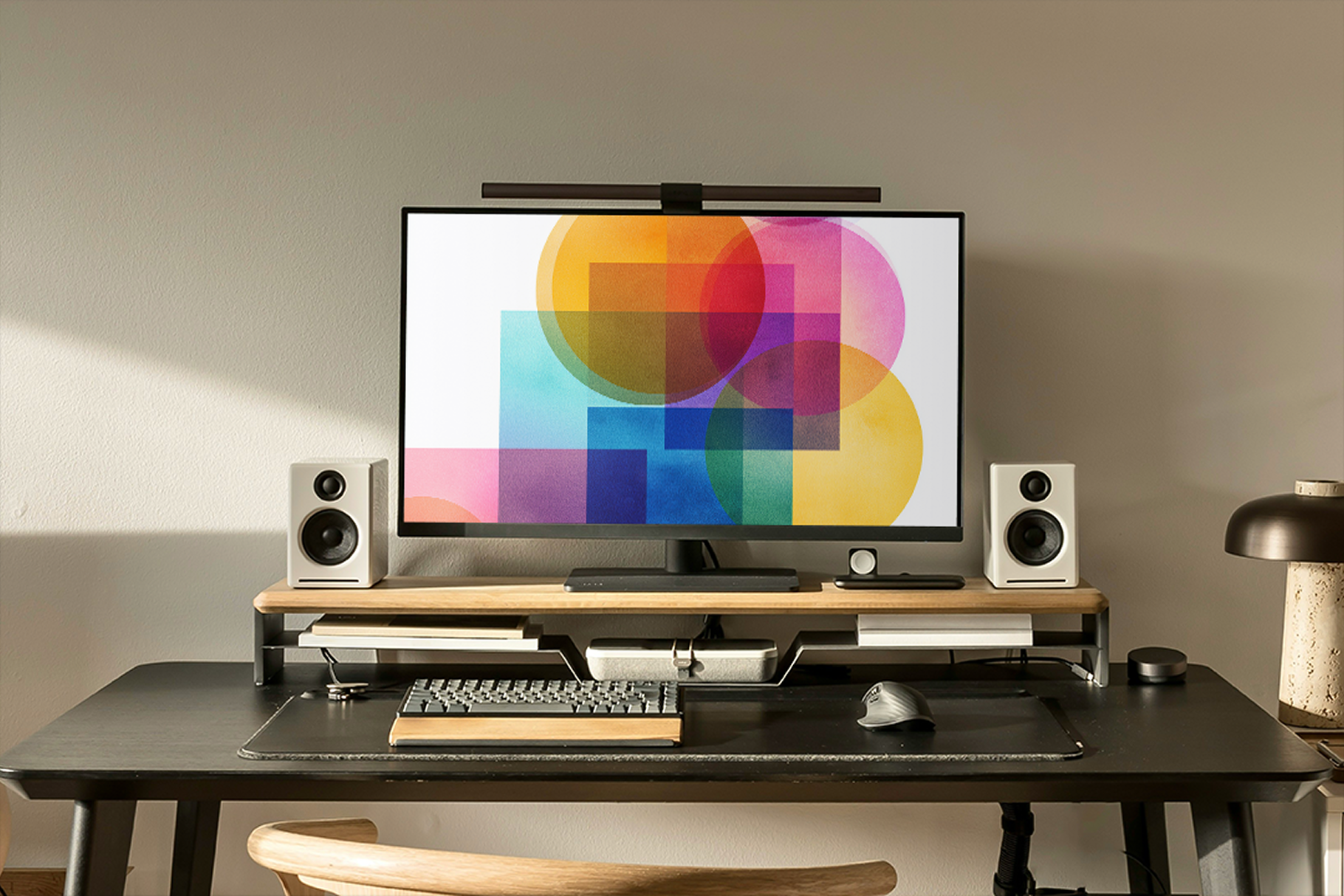 Modern home office setup with a computer monitor, keyboard, and speakers on a desk.