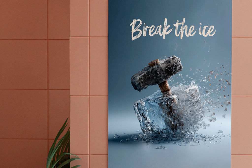 A vertical poster or print leaning against a terracotta tiled wall, featuring a large clear ice cube being smashed by a hammer with shattered ice particles around it. White script text at the top reads 'Break the ice.