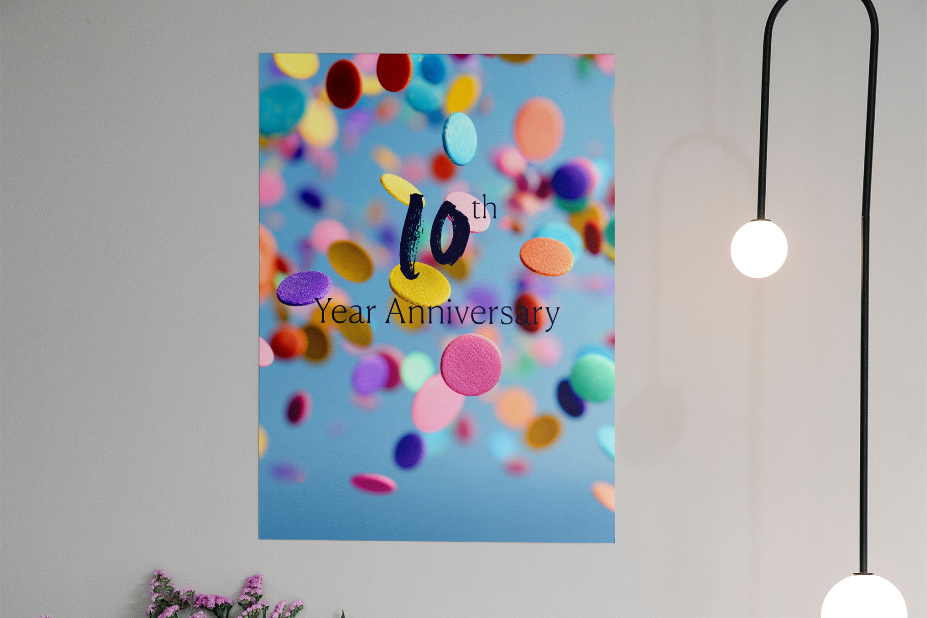 Poster with colorful confetti and '10th Year Anniversary' text on a light gray wall.