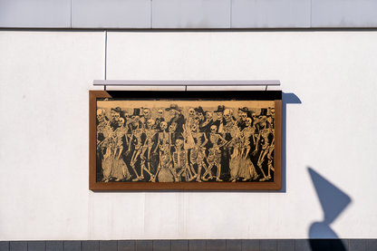 Framed artwork of skeletons in formal attire on a white wall