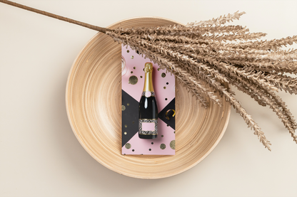 Bottle of champagne with decorative label on a wooden plate with dried flowers.
