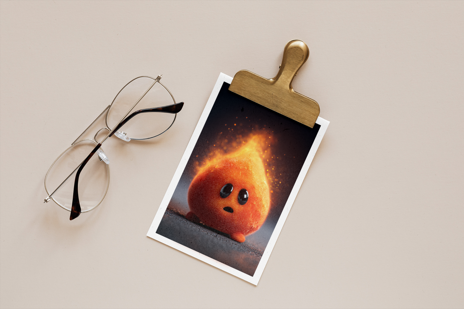 Clipboard with a photo of a droplet on fire, next to eyeglasses on a beige background