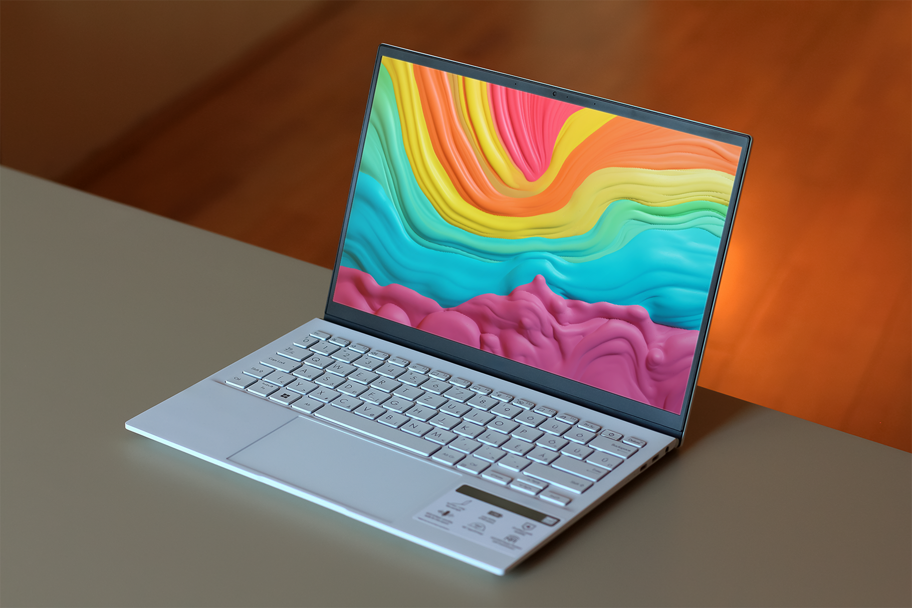 Laptop with a colorful abstract design on the screen, placed on a wooden surface.
