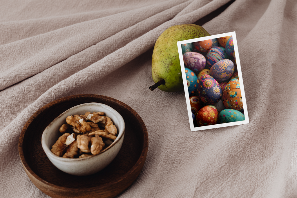 Bowl of nuts on a wooden plate with a pear and colorful Easter eggs on a beige fabric background