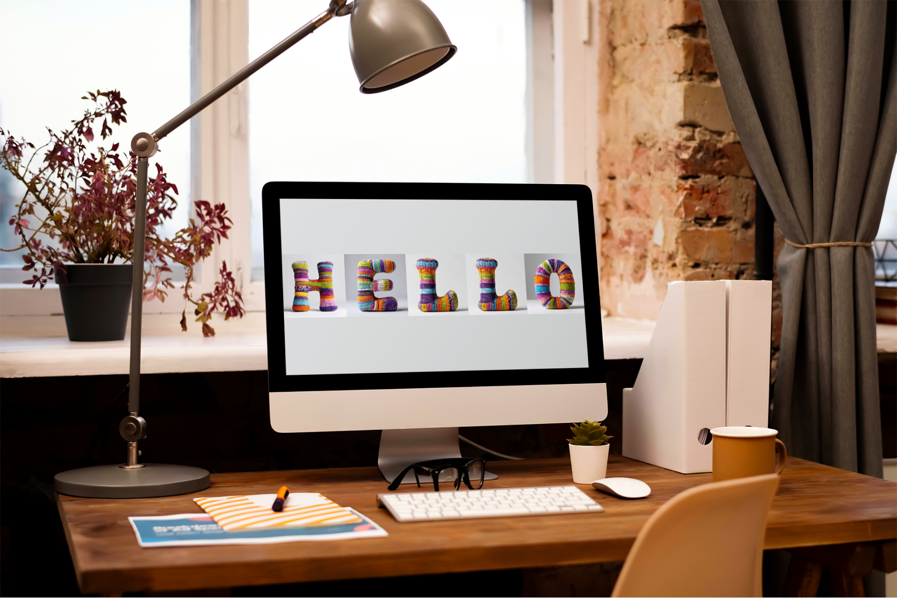 Home office desk with computer displaying 'HELLO' on screen, lamp, and decor.