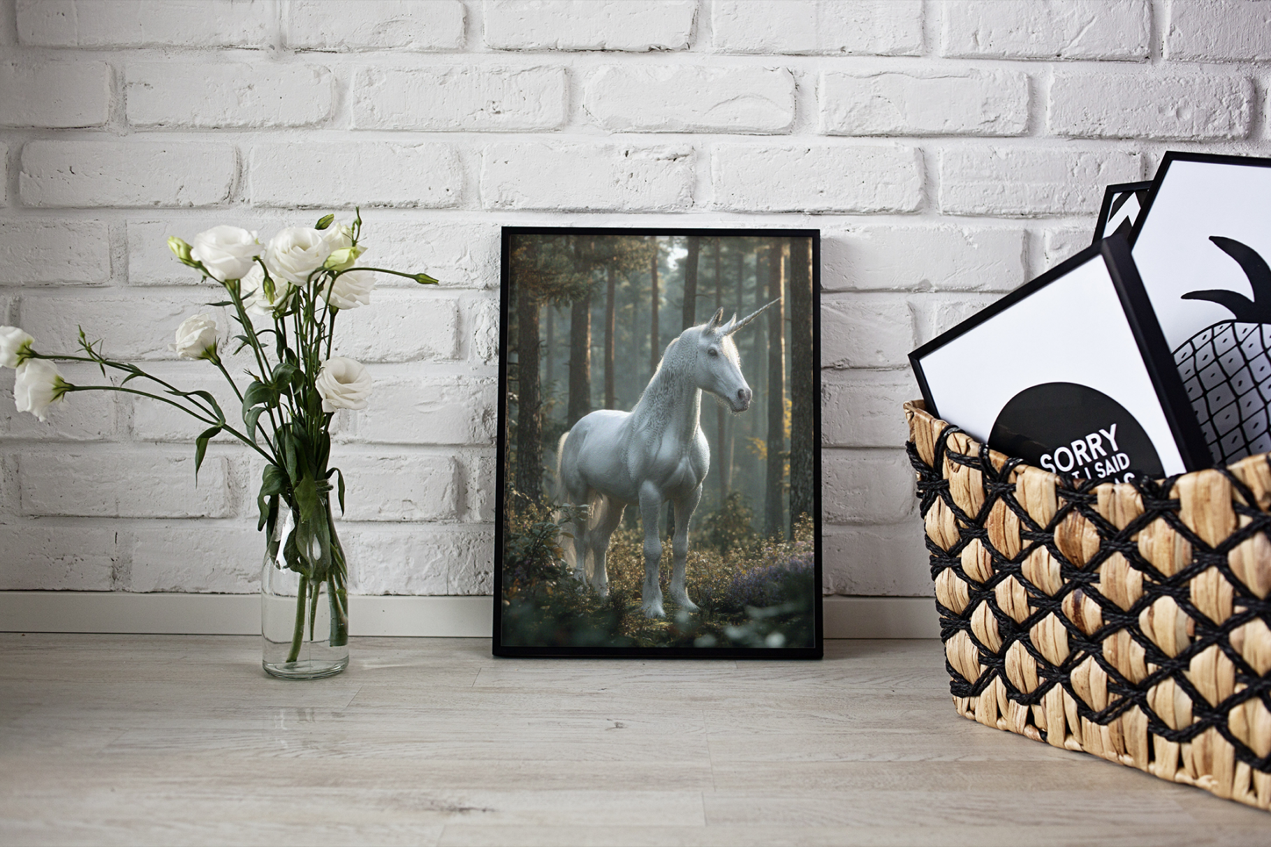 Framed picture of a unicorn in a forest on a white brick wall with a vase of flowers and a basket of books.