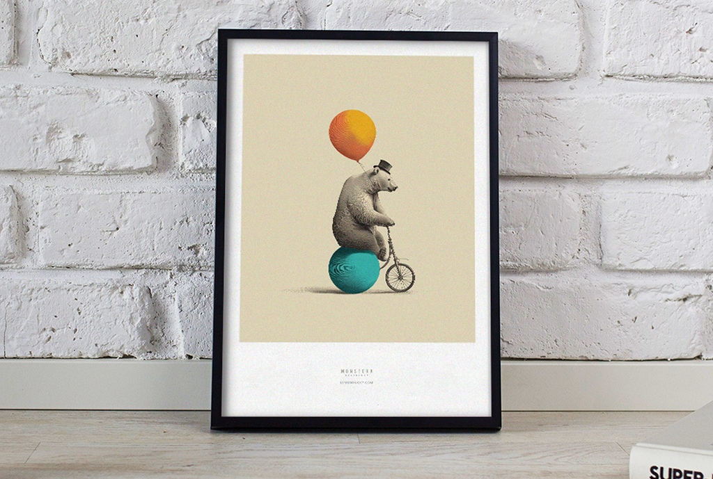 Framed artwork of a bear riding a bicycle with balloons against a brick wall.